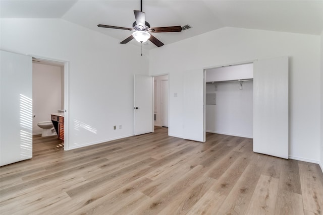 unfurnished bedroom with light wood-type flooring, lofted ceiling, a closet, ceiling fan, and connected bathroom