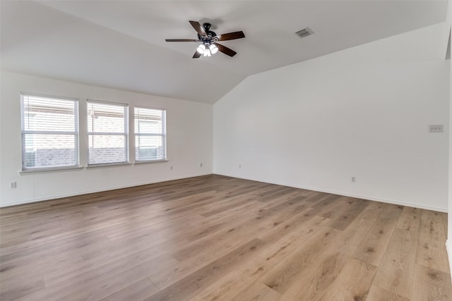 empty room with a ceiling fan, light wood-style flooring, baseboards, lofted ceiling, and visible vents
