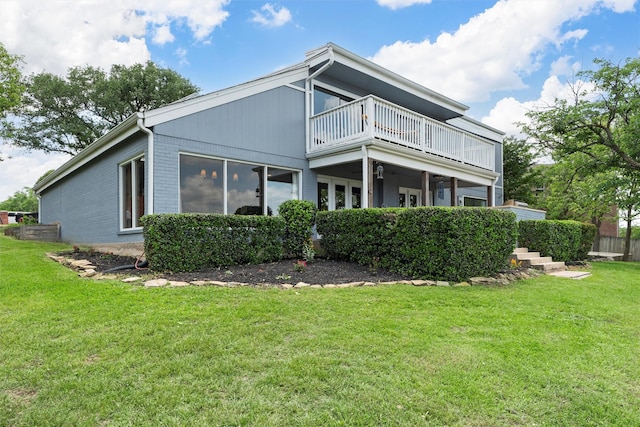rear view of house with a lawn and a balcony