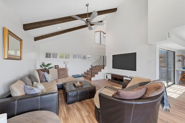 living room with stairway, high vaulted ceiling, a ceiling fan, light wood finished floors, and beam ceiling