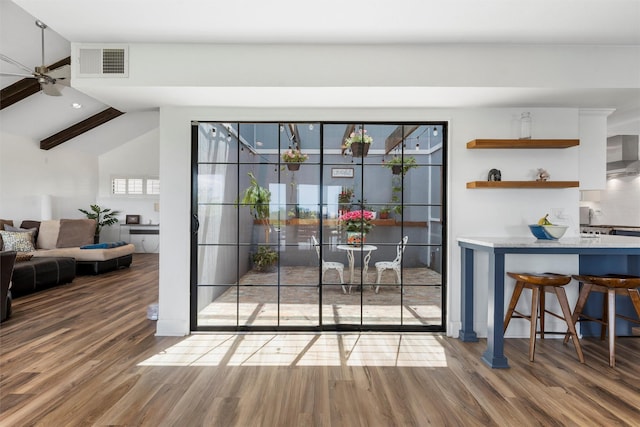 doorway to outside featuring ceiling fan, vaulted ceiling, wood finished floors, and visible vents