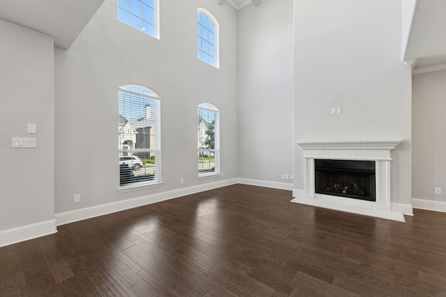 3213 Matisse Ln, Mckinney, TX 75070 - unfurnished living room featuring healthy amount of natural light, a towering ceiling, dark wood-type flooring, a fireplace with raised hearth, and baseboards