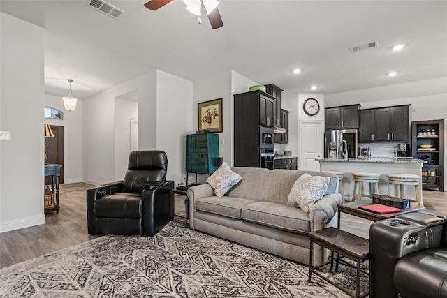 living room with recessed lighting, visible vents, light wood-type flooring, baseboards, and ceiling fan