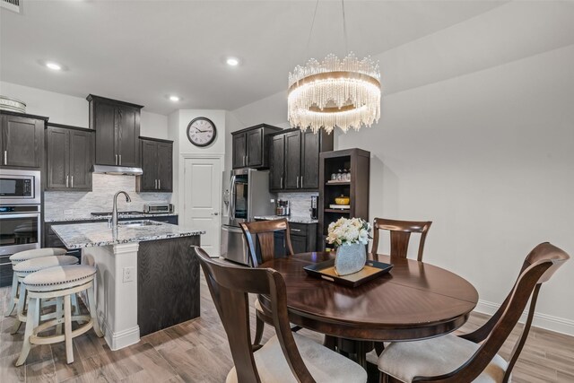 dining area featuring light wood-style floors, an inviting chandelier, a toaster, baseboards, and recessed lighting