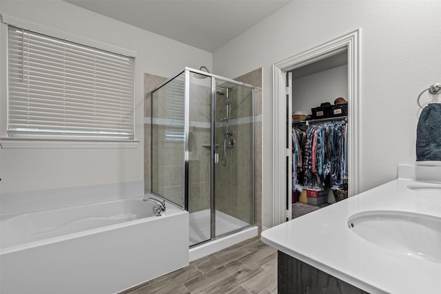 bathroom with a bath, wood finish floors, a spacious closet, and a shower stall