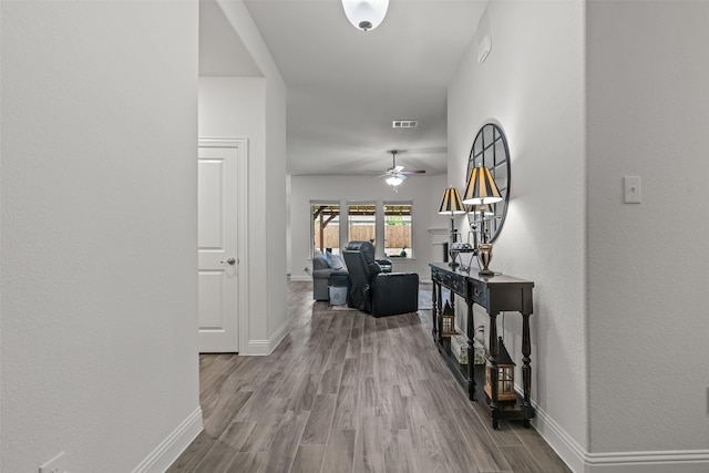 corridor featuring wood finished floors, visible vents, and baseboards
