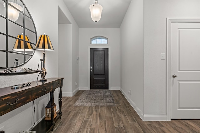 foyer featuring baseboards and dark wood-type flooring