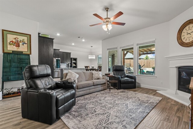 living area featuring recessed lighting, wood finished floors, a ceiling fan, baseboards, and a glass covered fireplace