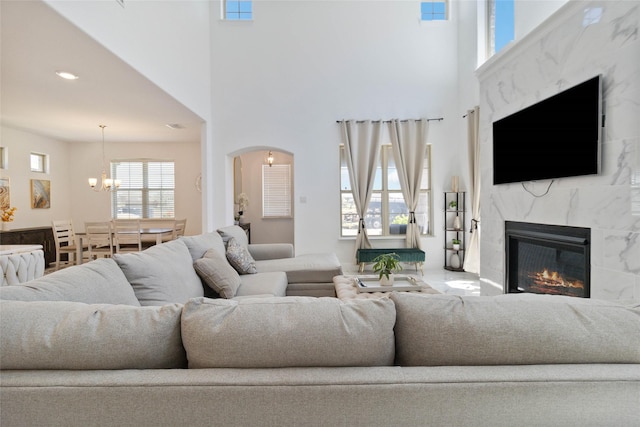 1313 Canuela Way, Justin, TX 76247 - living room with a high end fireplace, arched walkways, an inviting chandelier, a towering ceiling, and recessed lighting