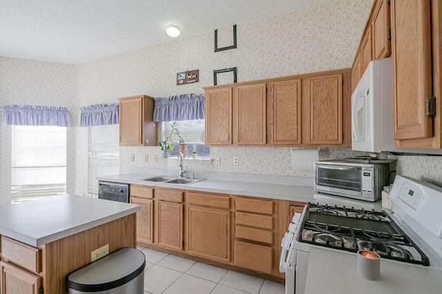 kitchen featuring light countertops, a sink, wallpapered walls, and white appliances