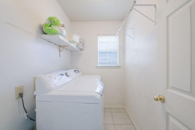 washroom featuring washing machine and clothes dryer, light tile patterned flooring, laundry area, and baseboards
