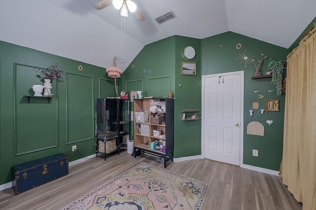 interior space featuring vaulted ceiling, a ceiling fan, wood finished floors, baseboards, and visible vents