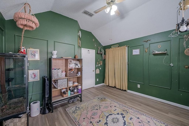 interior space featuring vaulted ceiling, a ceiling fan, wood finished floors, baseboards, and visible vents