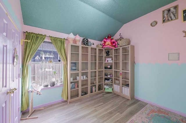 unfurnished room featuring lofted ceiling, wood finished floors, and baseboards