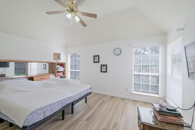 bedroom with lofted ceiling, multiple windows, a textured ceiling, and light wood-style floors