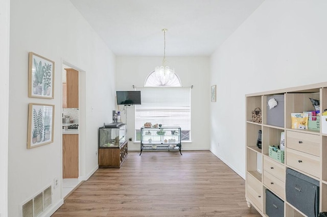 interior space with a chandelier, wood finished floors, and visible vents