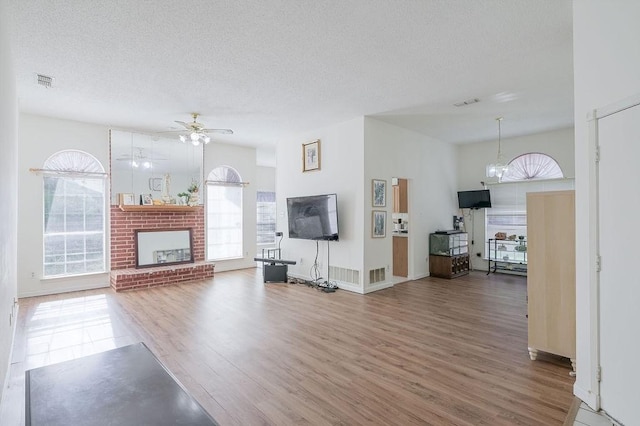 living area with a textured ceiling, wood finished floors, visible vents, and a fireplace
