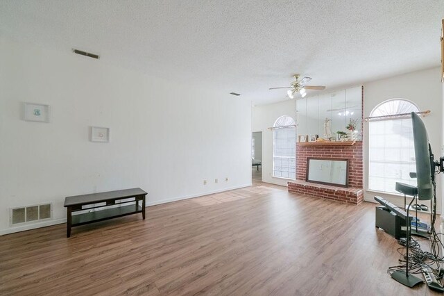 living room with a textured ceiling, baseboards, visible vents, a ceiling fan, and wood finished floors