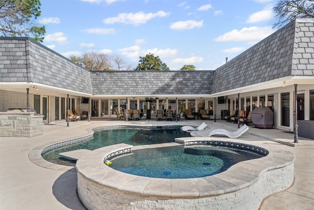 view of pool with an outdoor kitchen, a patio area, and a pool with connected hot tub