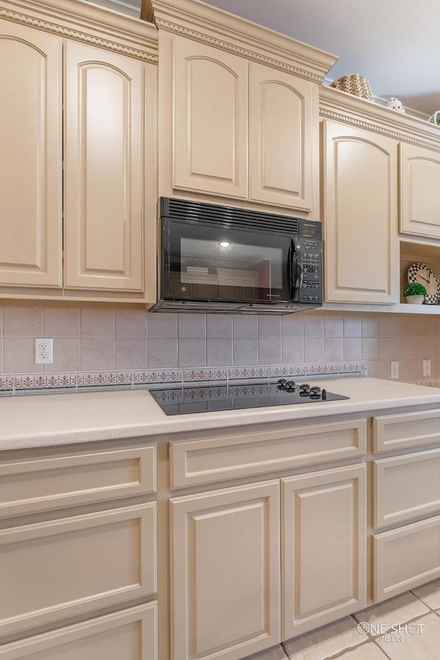 kitchen with decorative backsplash, cream cabinetry, and black appliances
