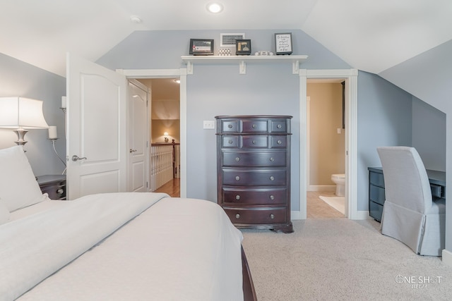 bedroom featuring vaulted ceiling, visible vents, connected bathroom, and light colored carpet