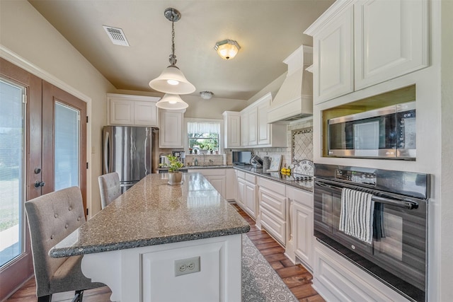 13043 W County Road 4182, Henderson, TX 75654 - kitchen featuring white cabinets, custom exhaust hood, stainless steel appliances, and visible vents