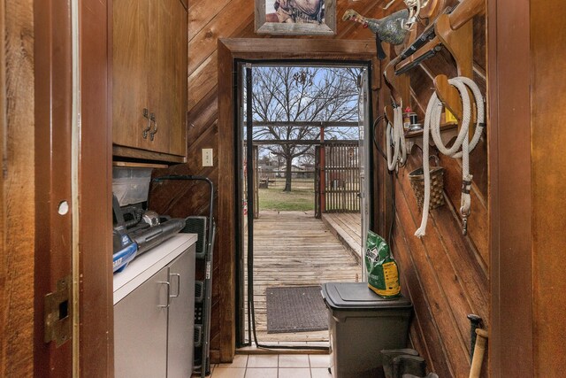 laundry area featuring separate washer and dryer, wood walls, and light tile patterned floors