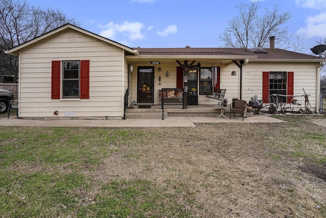 back of property with roof with shingles, covered porch, and a yard