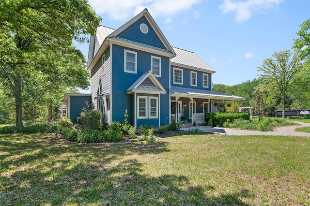 view of front of house with a standing seam roof, a porch, a front yard, and metal roof