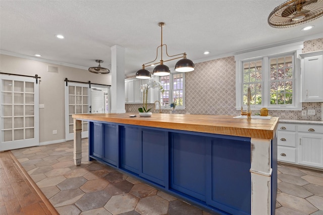 kitchen featuring a barn door, white cabinetry, crown molding, a breakfast bar, and wooden counters