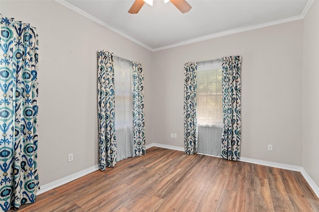 empty room with crown molding, wood finished floors, a ceiling fan, and baseboards