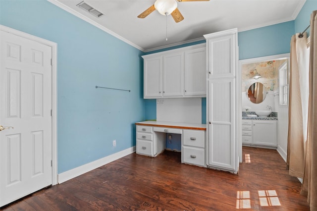 unfurnished office with visible vents, a ceiling fan, built in study area, dark wood-type flooring, and ornamental molding