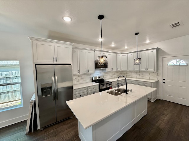 kitchen featuring stainless steel appliances, a sink, dark wood finished floors, visible vents, and decorative backsplash