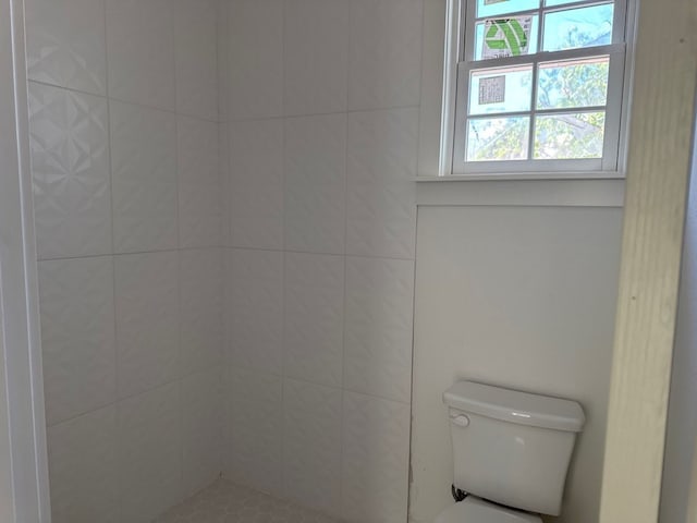 bathroom with a tile shower and toilet
