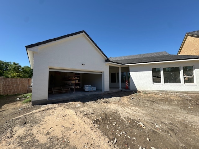 view of front of home with brick siding, an attached garage, and fence