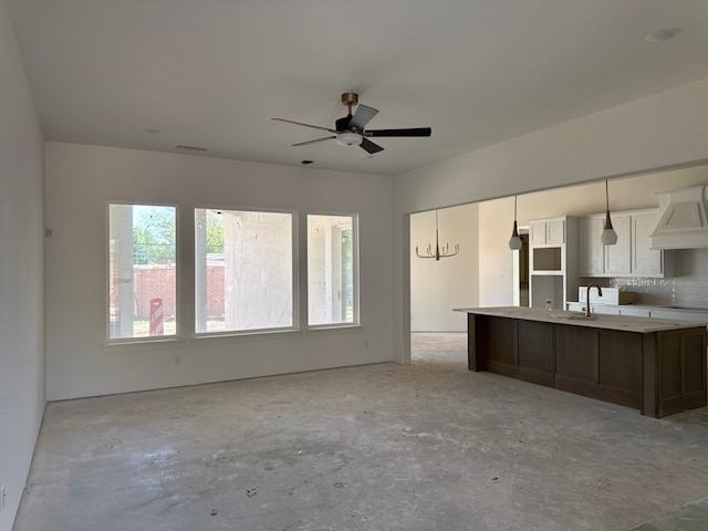 unfurnished living room with unfinished concrete floors, visible vents, ceiling fan, and a sink