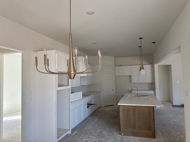 kitchen with white cabinets, concrete flooring, a sink, and a center island with sink