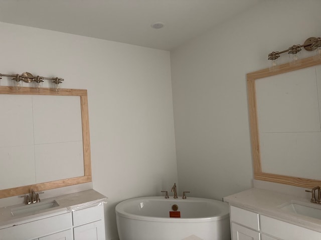 bathroom with two vanities, a freestanding tub, and a sink
