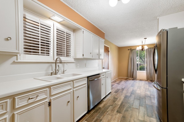 kitchen featuring wood finished floors, a sink, a textured ceiling, light countertops, and appliances with stainless steel finishes
