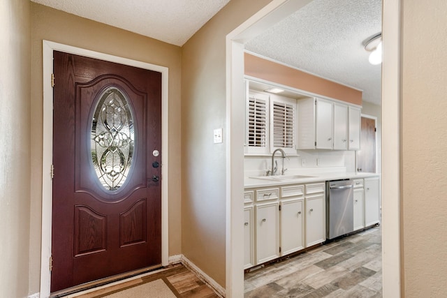 foyer with baseboards, a textured ceiling, and light wood finished floors