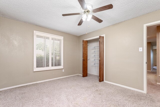 unfurnished bedroom with ceiling fan, carpet floors, a textured ceiling, and baseboards