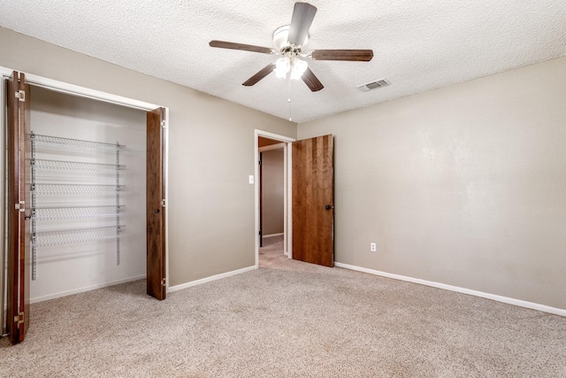 unfurnished bedroom featuring ceiling fan, a textured ceiling, visible vents, and carpet