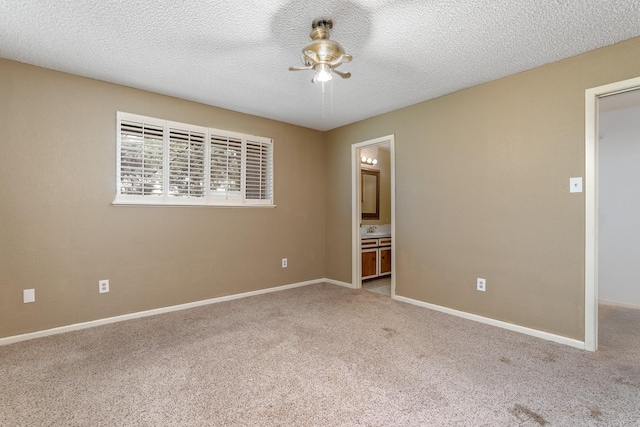 carpeted empty room with baseboards, a ceiling fan, and a textured ceiling