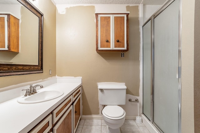 bathroom featuring toilet, a stall shower, vanity, baseboards, and tile patterned flooring