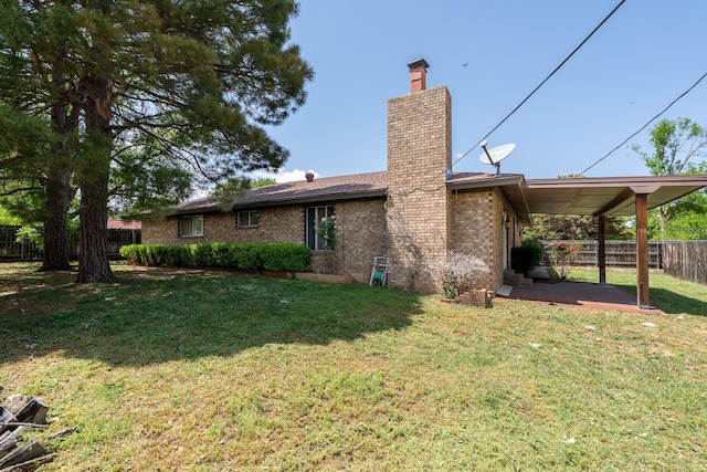 rear view of property with a chimney, fence, a yard, a patio, and brick siding