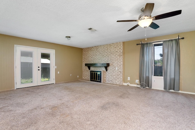 unfurnished living room with french doors, a brick fireplace, a textured ceiling, and ceiling fan