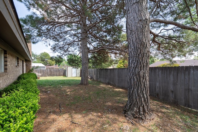 view of yard featuring a fenced backyard, an outbuilding, and a shed