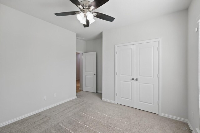 unfurnished bedroom with baseboards, carpet floors, a closet, and ceiling fan