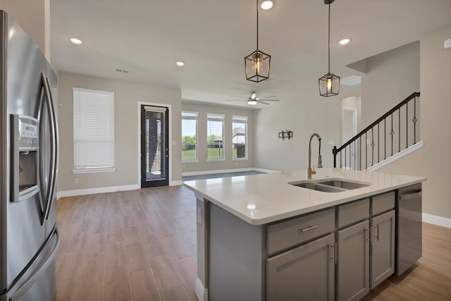 kitchen featuring stainless steel appliances, gray cabinets, a sink, baseboards, and ceiling fan