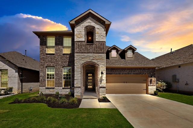 french provincial home featuring a garage, concrete driveway, stone siding, a front yard, and brick siding